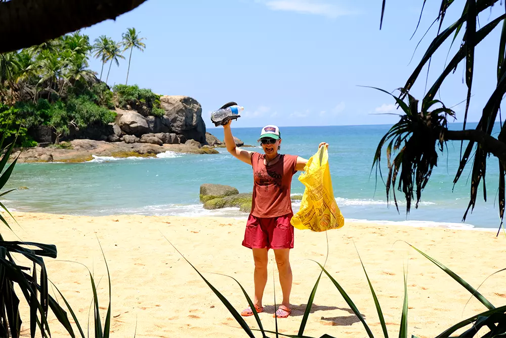 Volunteer Picking Up Rubbish During Beach Clean